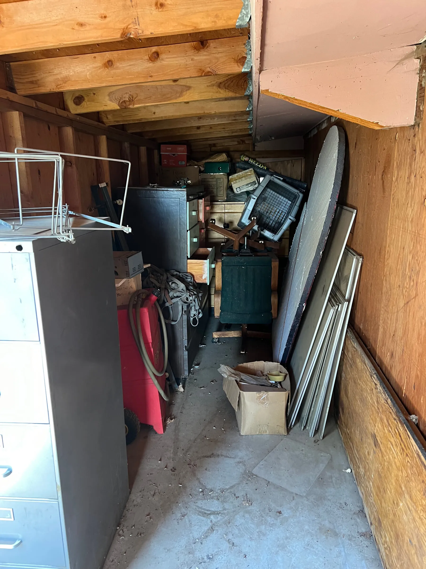 A garage stacked with old appliances, shelving and stored clutter