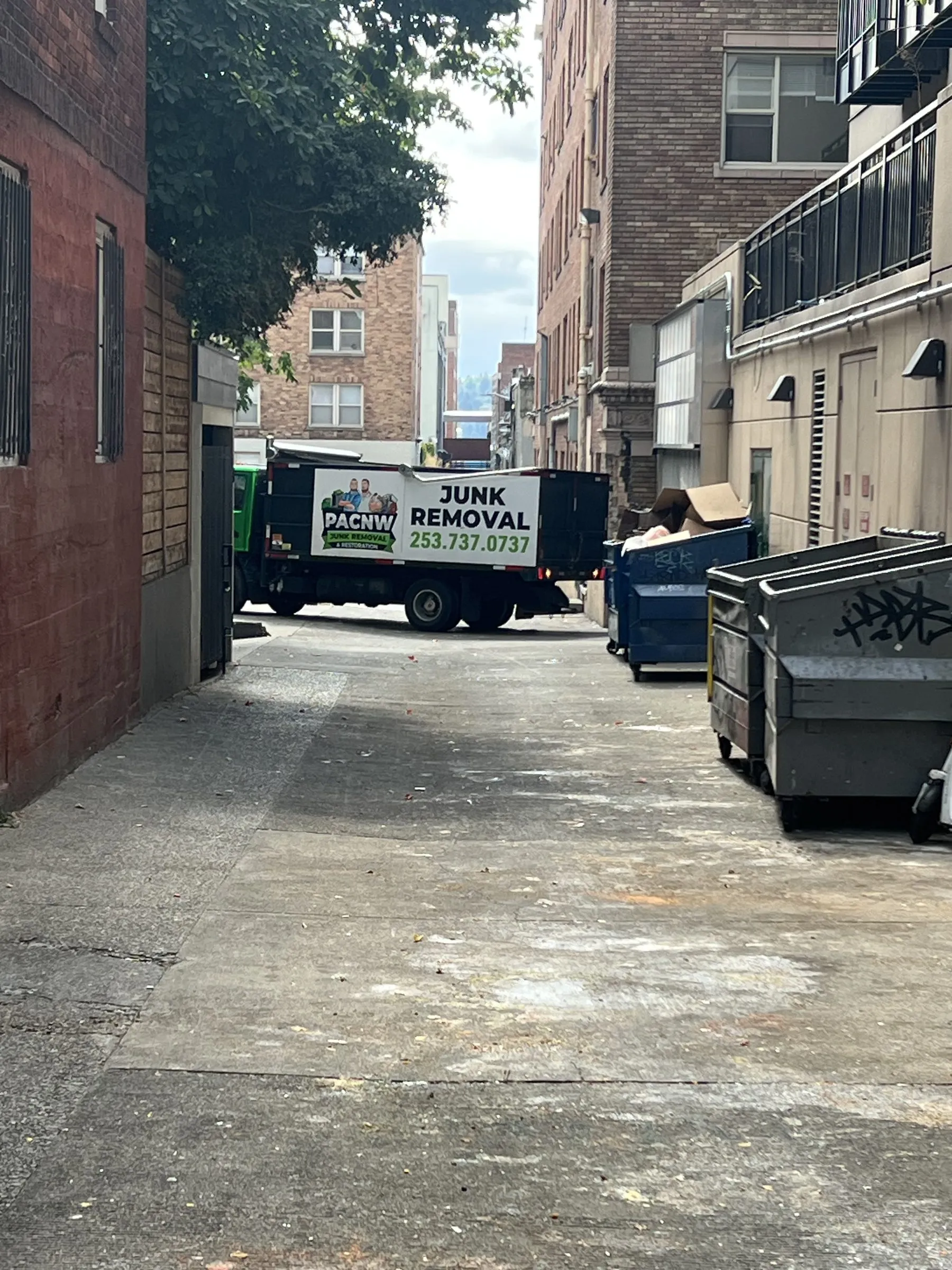 A PAC NW Junk Removal truck parked in the cleared alley at the end of the job
